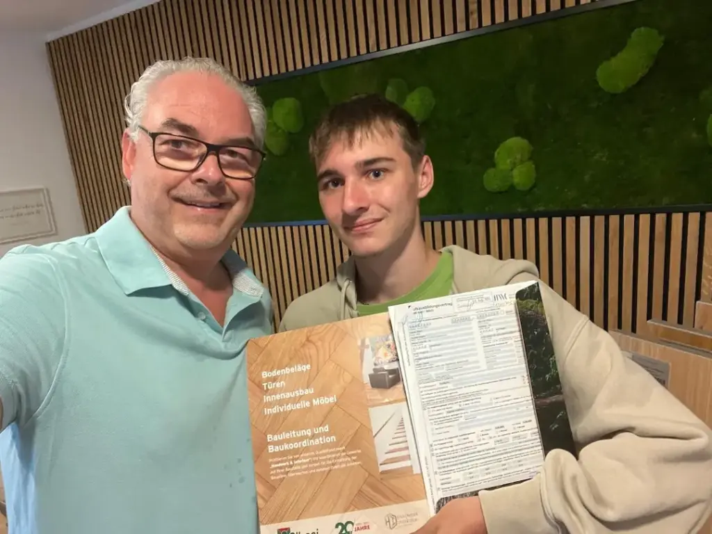 Daniel Albani mit dem neuen Auszubildenden Robin der seinen Ausbildungsvertrag in die Kamera hält.